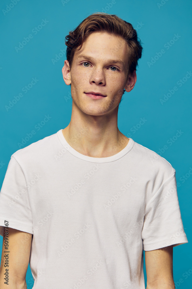 portrait of a handsome, cute guy in a white t-shirt on a blue background portrait of a handsome, cute guy in a white t-shirt on a blue background