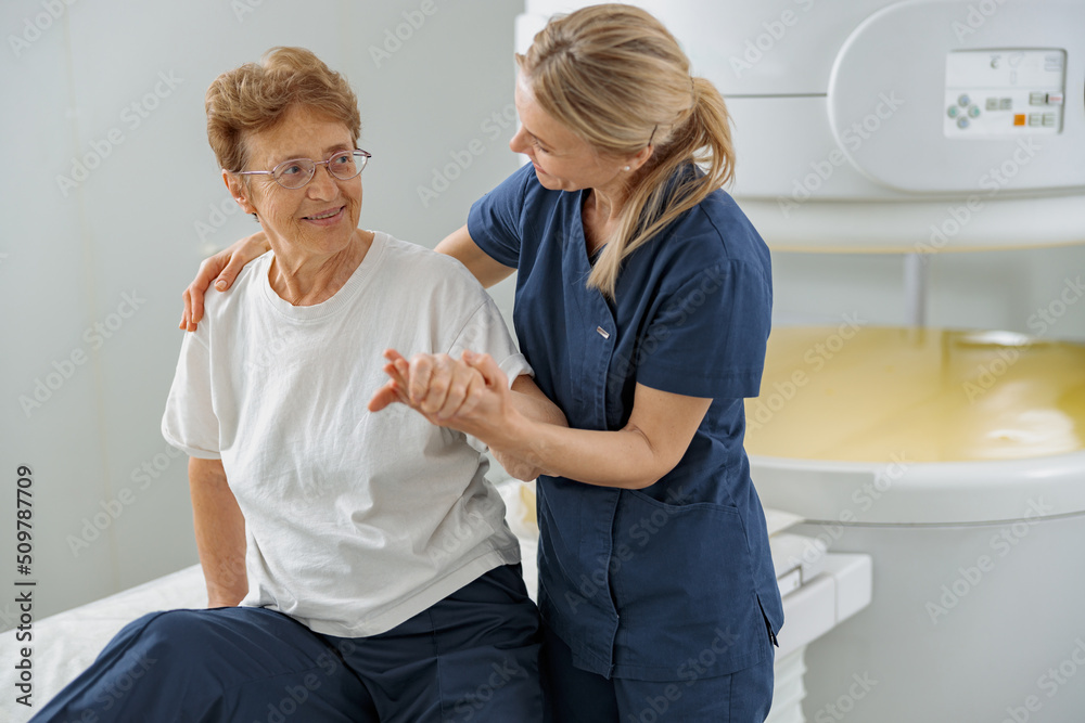 Fototapeta premium Radiologist help to patient sit after procedure of MRI or CT Scan . High Tech medical equipment