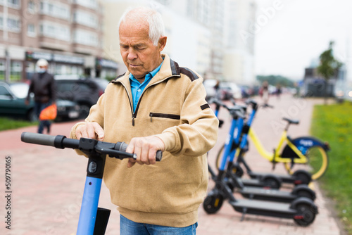 Portrait of mature man posing with electric scooter outdoor © caftor