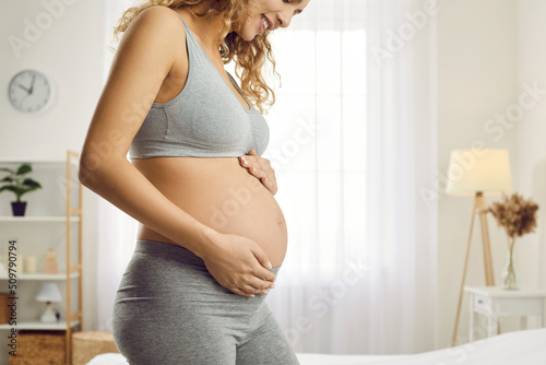 Obraz na płótnie Crop shot of smiling sporty healthy young woman touch caress belly excited with pregnancy await for baby birth