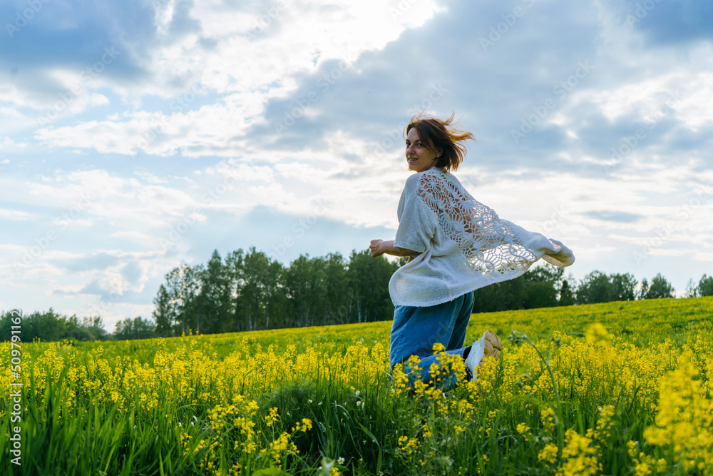 a young girl in a boho cape runs through a green field with yellow flowers