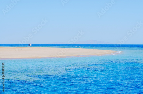 Seaview of the sandy beach on the island. Turquoise calm sea and white sand on a sunny day. Blue sea and sky background.