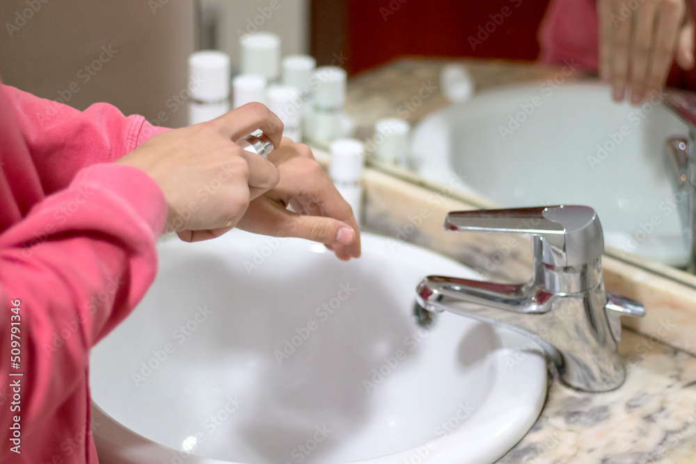 Woman spraying perfume on hands in the bathroom Woman spraying perfume on hands in the bathroom