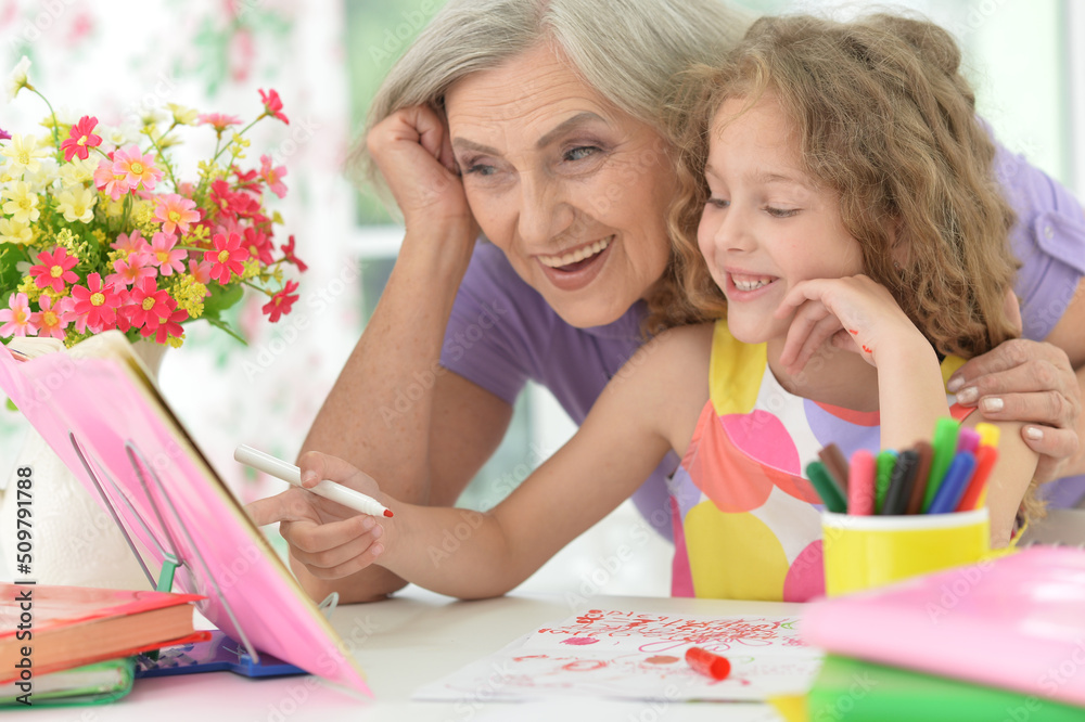 Little girl doing homework with her grandmother at home