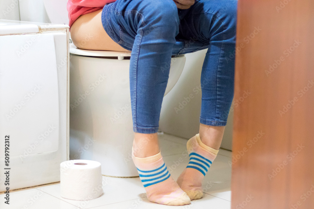 close up photo woman with constipation or diarrhea sitting on toilet with her pants down around her legs and a paper roll on the floor close up photo woman with constipation or diarrhea sitting on toilet with her pants down around her legs and a paper roll on the floor