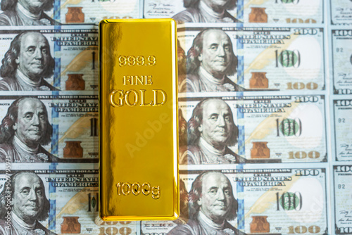 Precious shiny gold bar on dollar bills. gold reserve of the United States of America photo