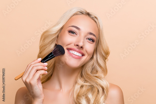 Photo of good mood stunning woman use maquillage brush on cheeks cheekbones isolated on beige color background