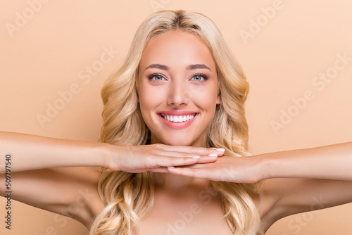 Portrait of attractive cheery well-groomed wavy-haired girl soft skin uplift cream effect isolated over beige pastel color background