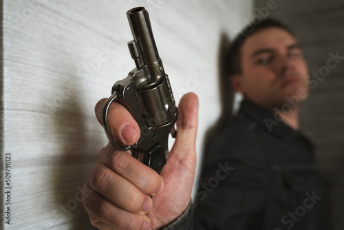 Threat to life. Close-up of hand with pistol. Shootout of criminals with revolvers. Killer or murderer. bandit hides in the dark with a firearm. shooter is in ambush photo