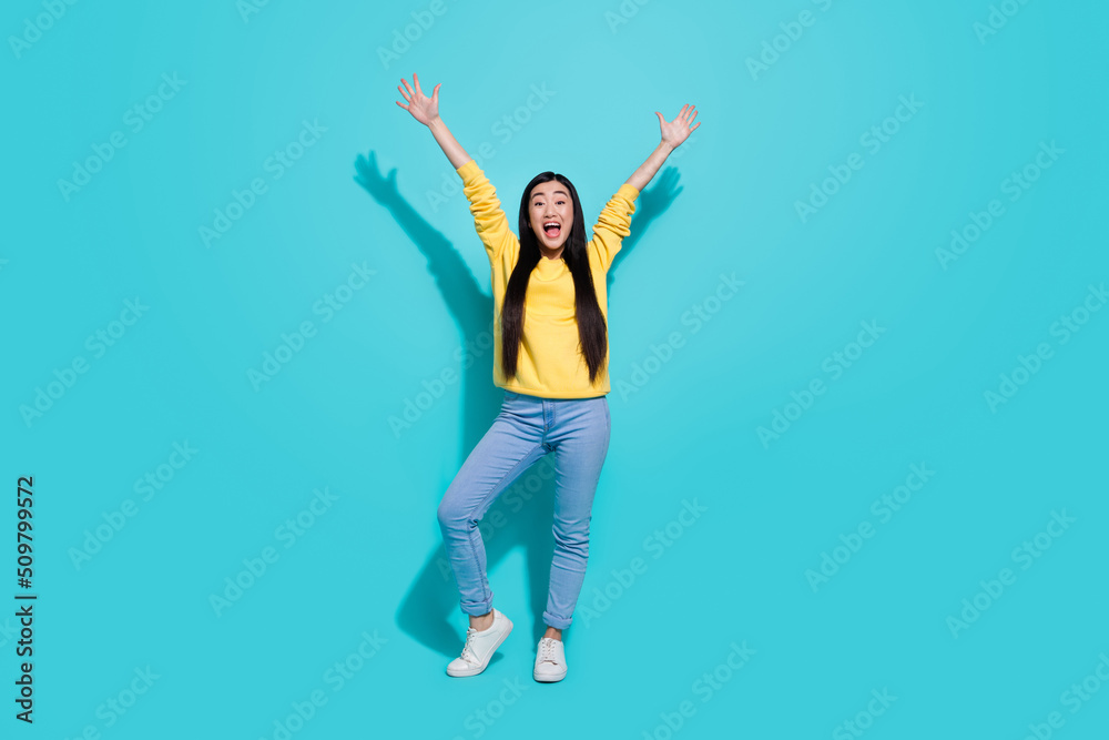 Full length photo of excited funny woman wear yellow pullover rising arms isolated teal color background