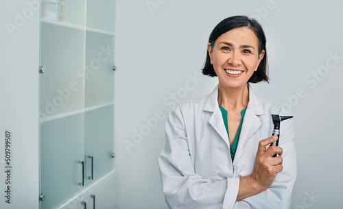 Woman audiologist with otoscope standing in medical clinic. Ear treatment and hear exam