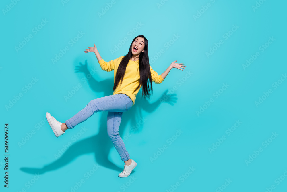 Full length photo of cute impressed woman wear yellow pullover dancing walking empty space isolated teal color background