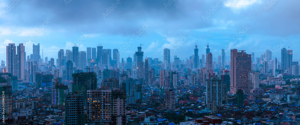 Fototapeta premium A cinematic evening in Mumbai when the sky was overcast with dark monsoon clouds about to burst over the city, and the dazzling city lights started coming alive in the mystic blues of twilight.