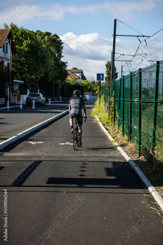 Piste cyclable avec un cycliste le long d une route  la piste est s  par  e par un trottoir  le sol poss  de un marquage blanc pour indiquer le sens des v  los