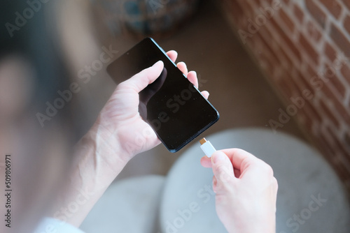 Frau lädt ihr Smartphone mit einem USB-C Ladekabel