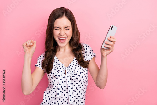 Photo of funky overjoyed girl raise fists in victory win in social media phone giveaway isolated on pink color background