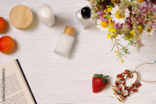 Cosmetic bottles, fruit flowers and book on table, lifestyle staging