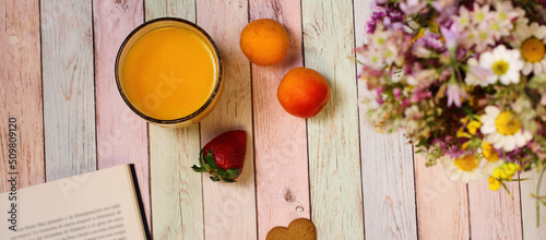 Juice, apricots and book on colorful table, copy space