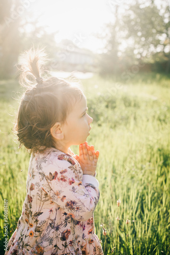 Candid portrait of little girl in a field. Sunshine on the face 