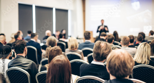 Speaker giving a talk in conference hall at business event. Rear view of unrecognizable people in audience at the conference hall. Business and entrepreneurship concept.