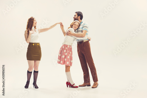 One young man and two girl in vintage retro style outfits psoing isolated on white background. Concept of relationships, family, 1960s american fashion style and art.