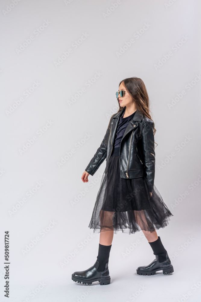 stylish teenage girl with dark hair, dressed in fashionable clothes, a leather jacket and sunglasses on white wall. full growth. concept of youth and clothing. stylish teenage girl with dark hair, dressed in fashionable clothes, a leather jacket and sunglasses on white wall. full growth. concept of youth and clothing.