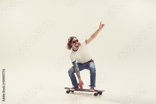 Stylish young man, hipster dressed in 50s, 60s fashion style posing with longboard isolated on white background. Retro vintage style, business, ad, emotions