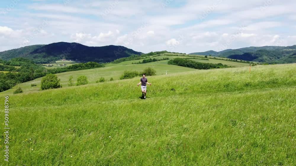 Brown-haired athlete jumps over a jump rope at the top of a hill in summer weather. Warming up before a hard endurance training. Warm up of muscles. 4k video Brown-haired athlete jumps over a jump rope at the top of a hill in summer weather. Warming up before a hard endurance training. Warm up of muscles. 4k video
