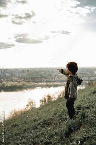 a child stands on a mountain and looks at the river © Anastasia Amraeva