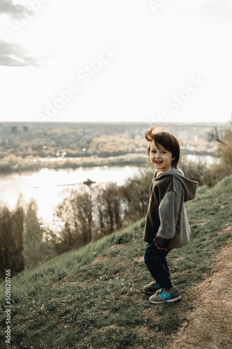 a child stands on a mountain and looks at the river © Anastasia Amraeva