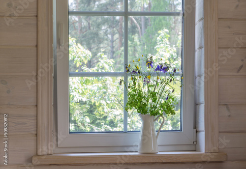 White window with mosuito net in a rustic wooden house