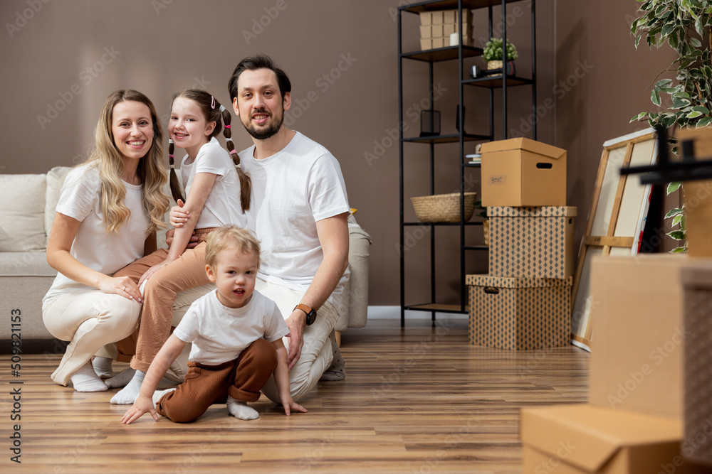 Mortgage, family and real estate - happy mother, father, young daughter and son with stuff in boxes, moving to new house.