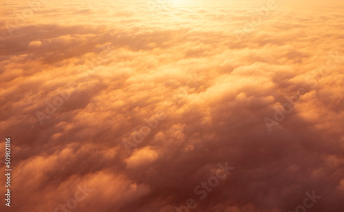 Aerial top view gold sunrise over clouds. Aerial top view cloudscape. Texture of clouds. View from above. Orange sunrise or sunset over clouds. Panorama clouds texture