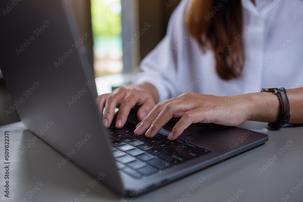 Closeup image of a woman working and typing on laptop computer keyboard in office