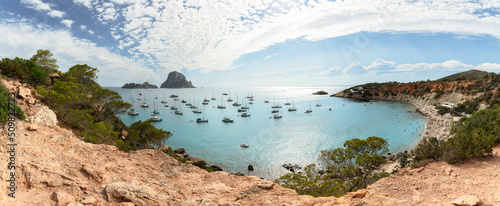 Maxi panoramic shot of a horseshoe-shaped bay Cola d'Hort, pre-sunset sun whitened water with its rays, Ibiza, Balearic Islands, Spain