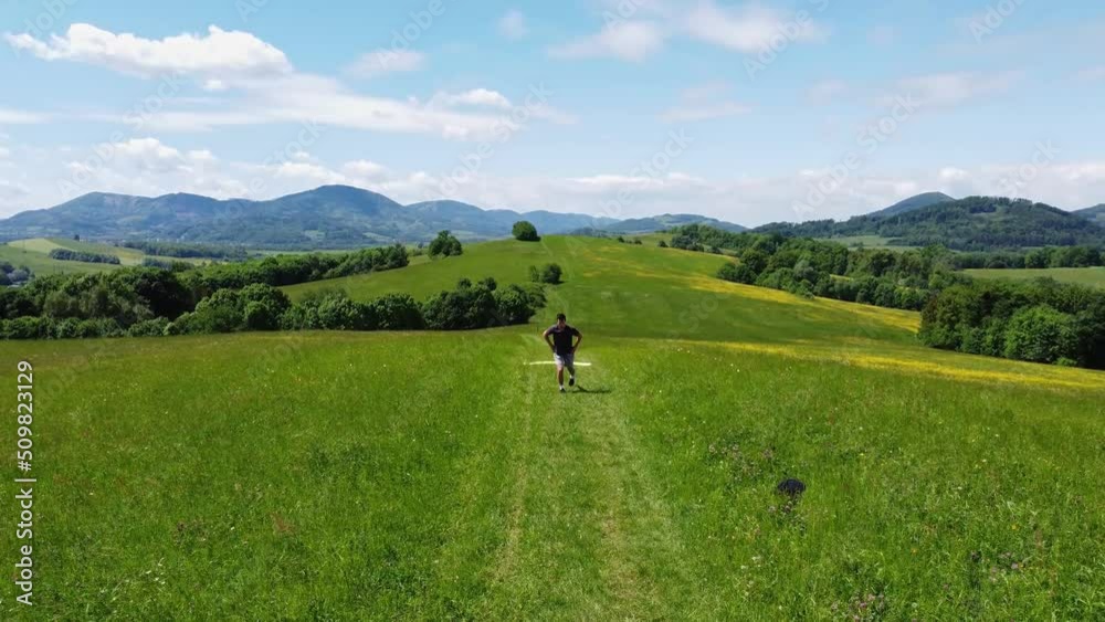 Brown-haired athlete stretches his groin and exercises his lower body with front lunges at the top of a hill in sunny weather. Warming up before the game. 4k video Brown-haired athlete stretches his groin and exercises his lower body with front lunges at the top of a hill in sunny weather. Warming up before the game. 4k video