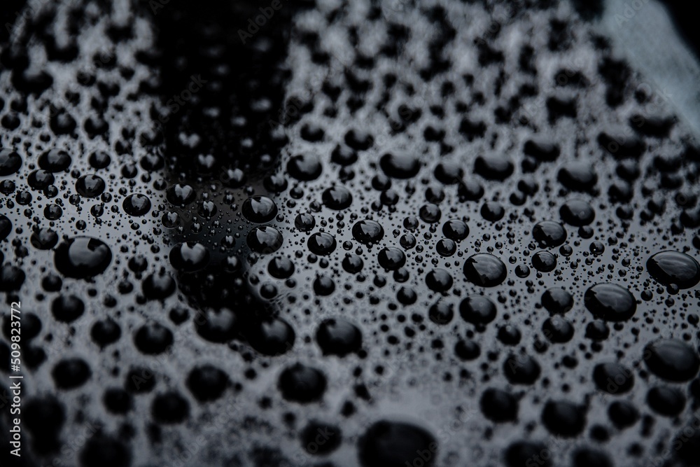 Close up on ideal water drops after rain on car body after using ceramic coating