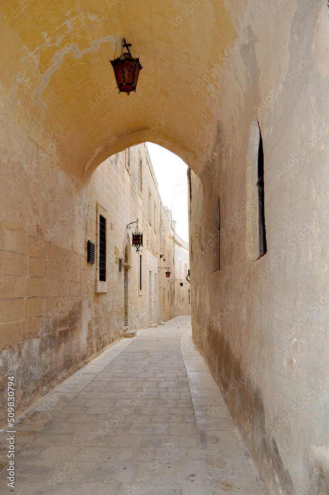 Narrow street with ancient stone houses and antique lantern on the wall in Mdina,also called Silent City. Malta, Europe. 