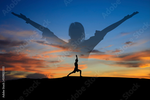 Silhouette of young man practices yoga and meditates on top of the mountain with double exposure young woman standing and open arm and feel free with bird over the sky at sunset in summer season.