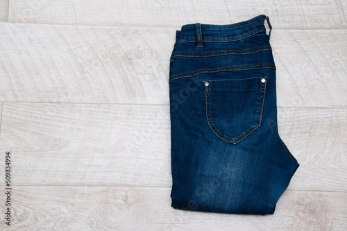 Dark blue women's jeans on a light wooden background