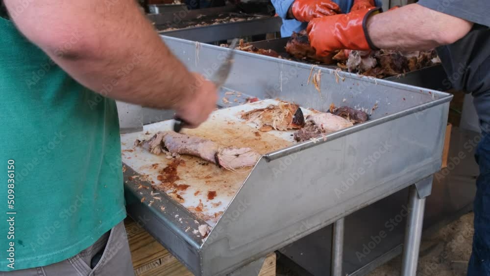 Man chopping BBQ with large knife at a chopping table Man chopping BBQ with large knife at a chopping table