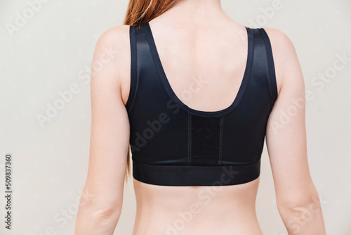 A young woman in black compression underwear after mammoplasty.