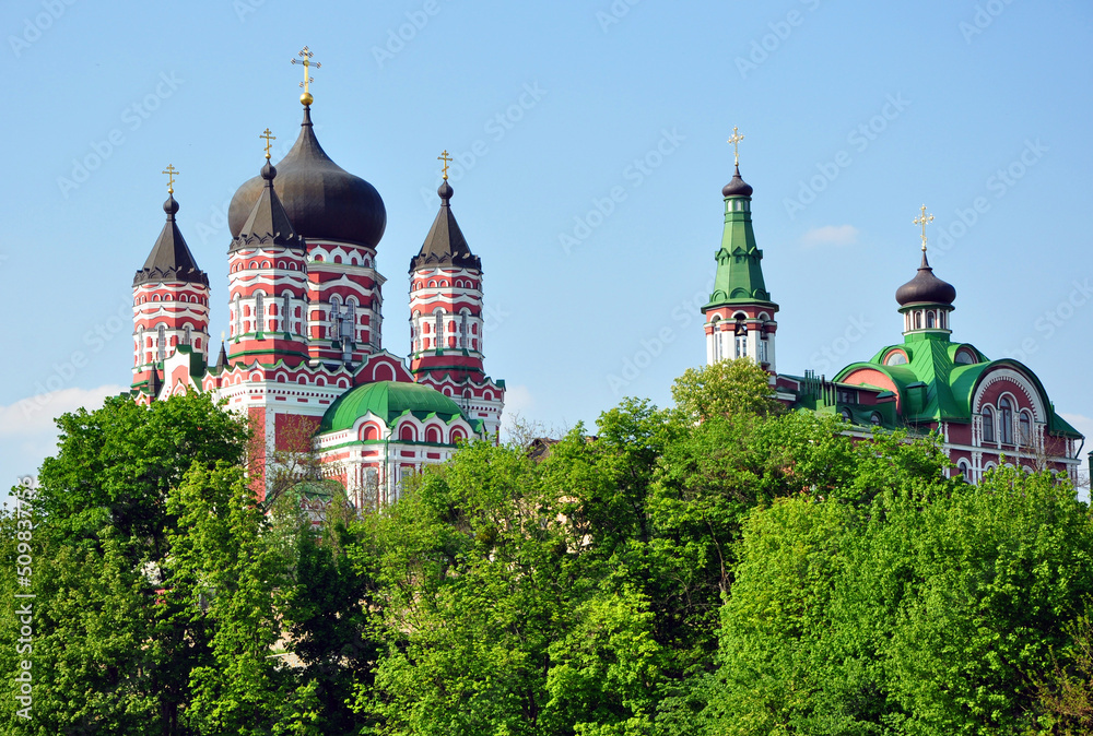 Domes or cupolas with Eastern Orthodox crosses of monastery churches seen through trees on sky