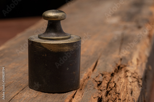 Antique brass scale weight on rustic wood texture, labeled Libra 1/4