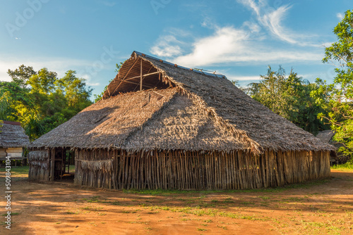 A tribal meeting hall built with wood and leaves by indigenous people deep in the Amazon rainforest. This is the main activity place of the primitive tribe. © William Huang