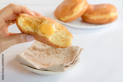 Bolas de Berlim, Berliner or donuts filled with egg jam, a very popular dessert in Portuguese pastry shops. Person tasting a berlin ball. photo