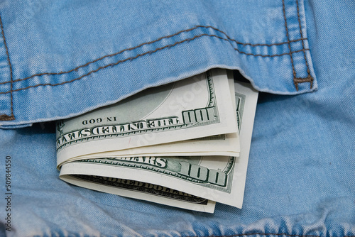 Dollars in the back pocket of denim pants close up