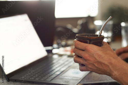 Young man works at home while drinking yerba mate photo