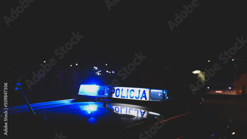 Police emergency lights flash at night. Car accident. Crime scene.  Flashing blue lights on patrol car. Police car in Poland with the lettering "Policja"