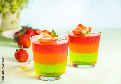 Glasses of tasty summer dessert layered colorful jelly with fresh strawberries